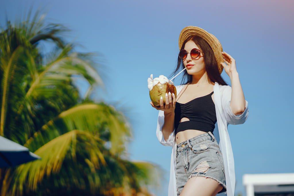 girl drinking fresh juice from a coconut by the pool